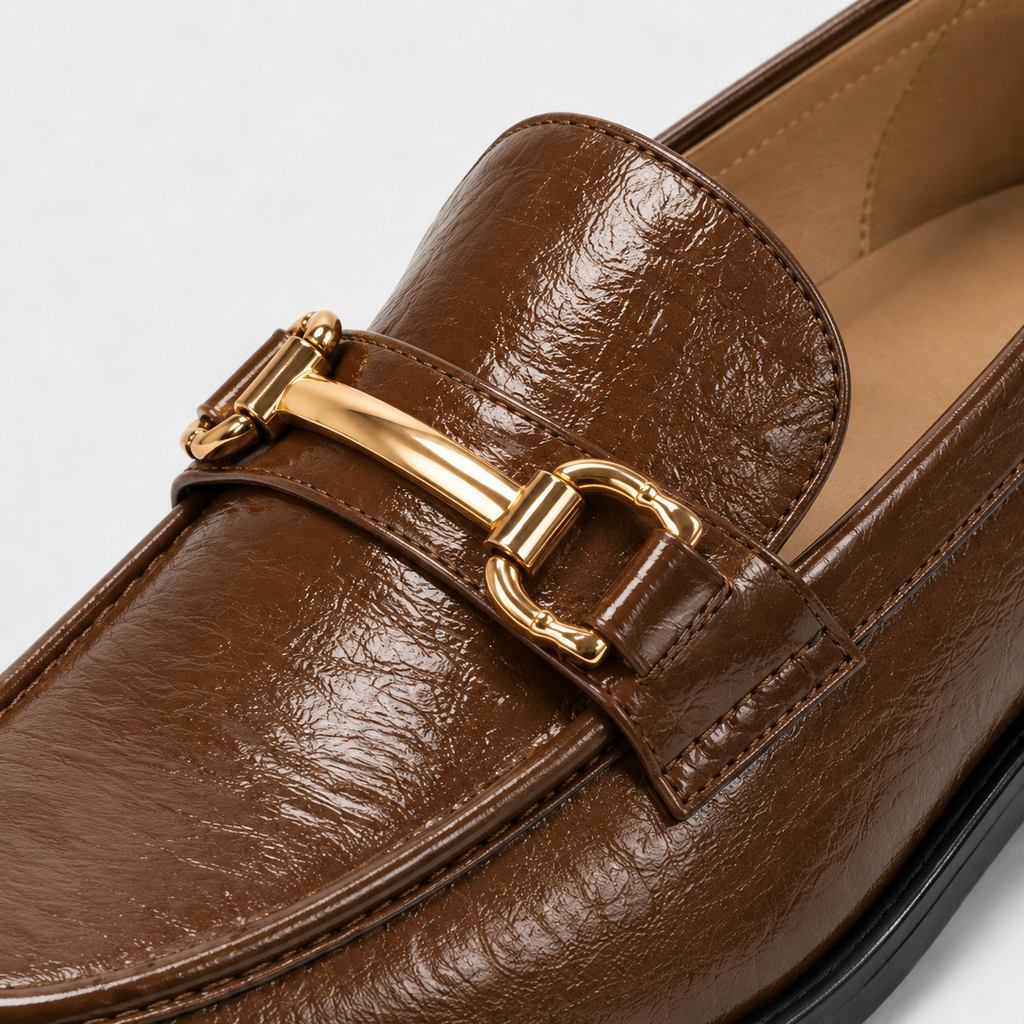 Gold-tone horsebit detail on glossy brown loafers