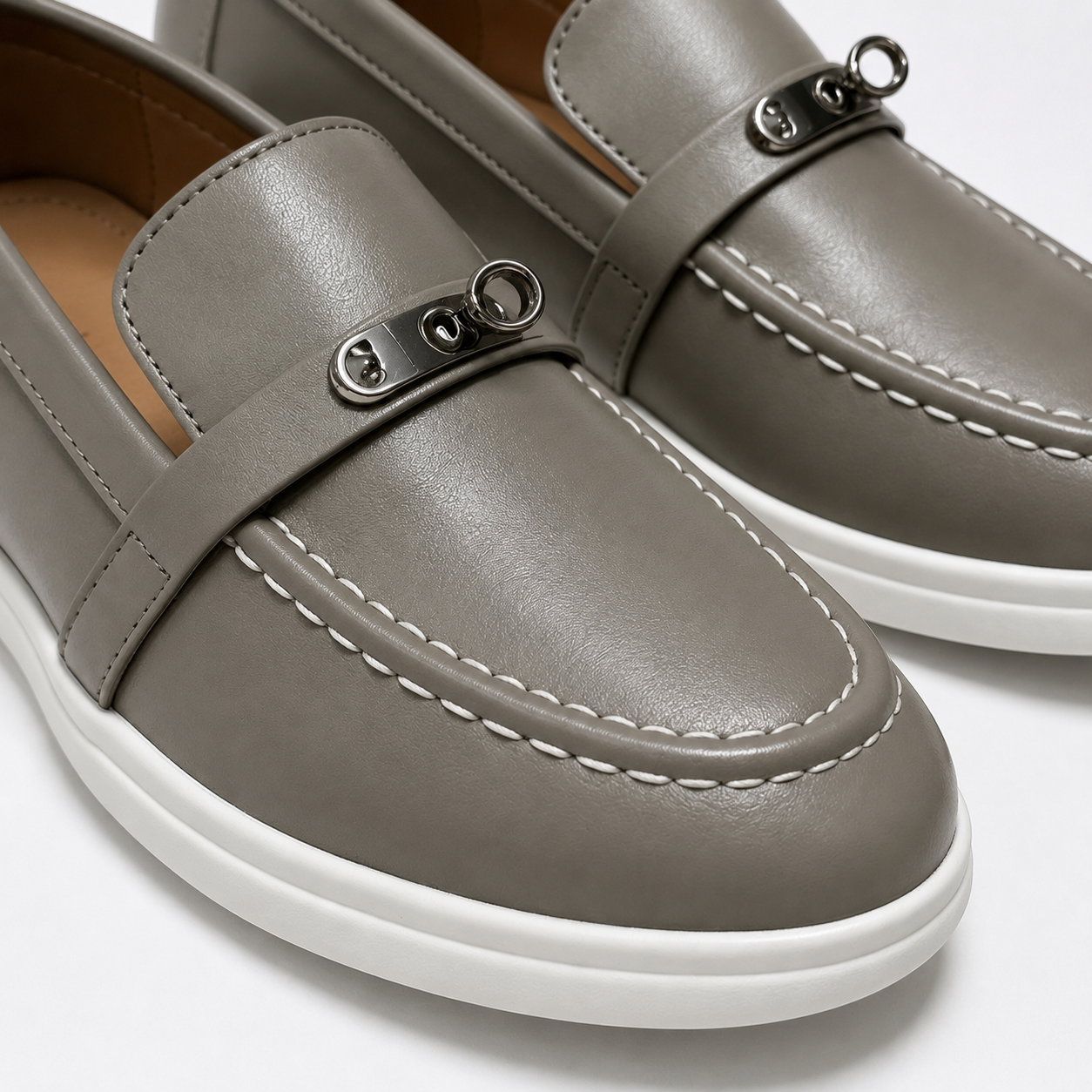 Metal accent and contrast stitching detail on taupe loafers